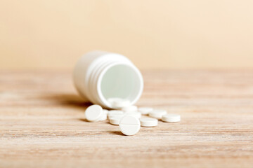 Medicine bottle and white pills spilled on a light background. Medicines and prescription pills flat lay background. White medical pills and tablets spilling out of a drug bottle