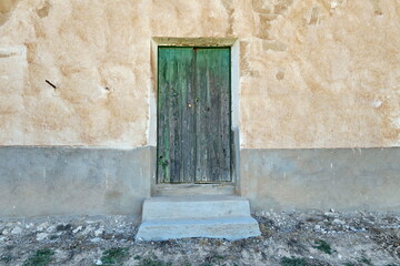 Fototapeta na wymiar Ancienne porte en bois délavée sur façade de ferme.