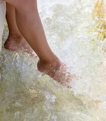 Legs of a girl in the clear water of a stream.