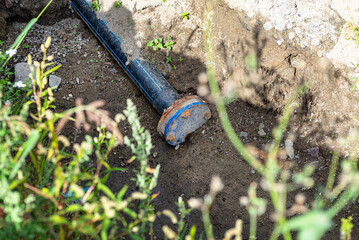 Closed end of a plastic water pipe lying along a ditch with high groundwater, water connection on...