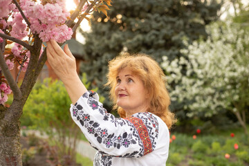 senior ukrainian woman in summer or spring park with sakura tree