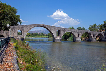 Fototapeta na wymiar The Bridge of Arta. A stone bridge that crosses the Arachthos river in the west of the city of Arta in Greece. Sunny summer day with blue sky