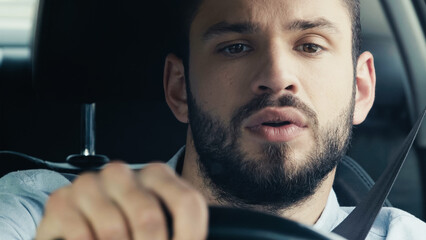 young and concentrated man driving car and looking ahead.