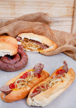 South African famous boerewors rolls with fried onions on grey surface with burlap and rustic wood