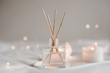 Home aroma fragrance diffuser with burning candles on white tray in bed over glowing lights close up. Cozy atmosphere. Wellness. Healthy lifestyle.