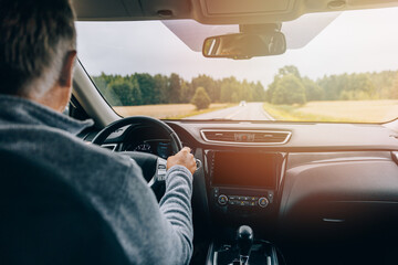 Man driving car on the country road with sunlight. Rear view