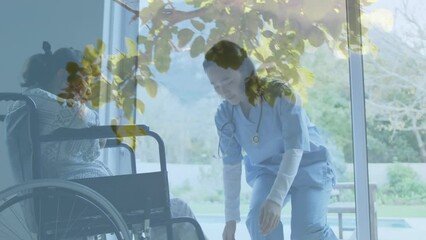 Animation of leaves over asian nurse with patient in wheelchair