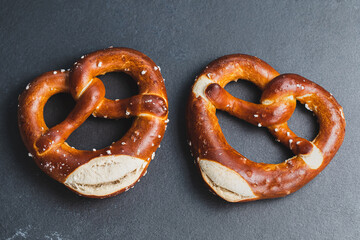 Two traditional soft Octoberfest pretzels on black background