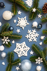 White Christmas decorations and fir branches on a blue background top view