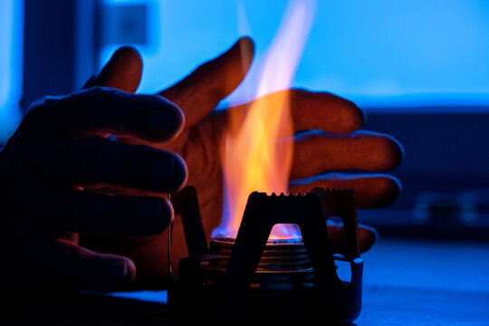 a man warmed his hands from an alcohol lamp in the absence of heating concept of the energy crisis in Europe caused by the rejection of fossil fuels. Blackout