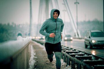 runner in motion fast running over the bridge at the winter snowy weather. Sportsman workout on...