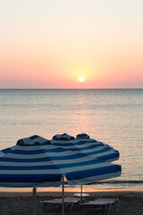 Parasol and sun loungers at sunrise by ocean