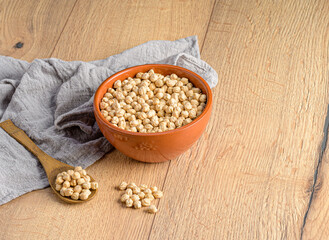 a bowl with chickpeas next to a wooden spoon with chickpeas