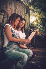 Two girls spend time together using a tablet device. Walking, friendship, music and leisure time.