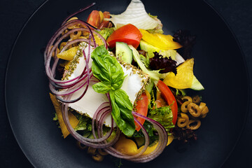 Greek salad on a dark plate, on a dark background