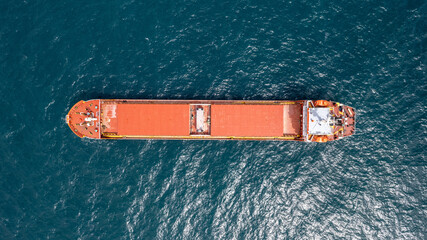 Unloaded red cargo ship anchored in calm water.