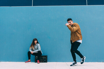 Young happy couple dancing on the street with a vintage radio cassette stereo .