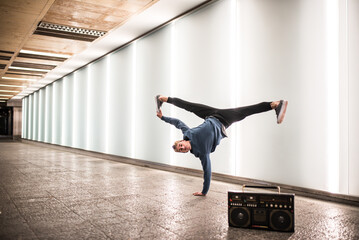 Happy young man dancing and jumping in the street with a vintage radio cassette stereo .