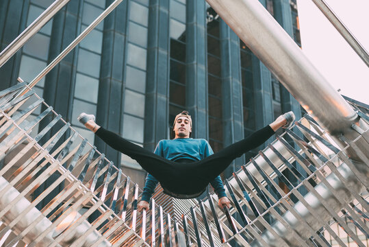 Happy Young Man Doing Acrobatic Poses In A Metal Sculpture .