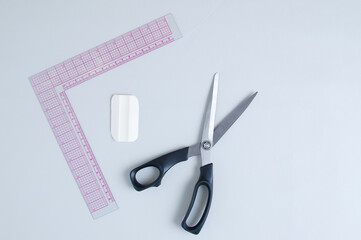 Cutter ruler, scissors and chalk on a gray leather background.