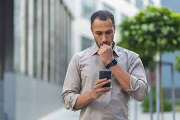 Thinking and sad muslim businessman reading message from smartphone, man outside office building using phone depressed reading bad news