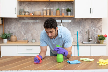 Handsome man cleaning kitchen. Young husband in household concept	