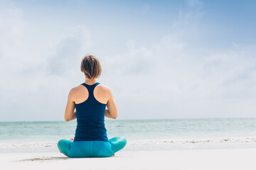 Caucasian woman practicing yoga at seashore