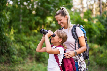 Mother and daughter using binoculars and enjoy hiking together.