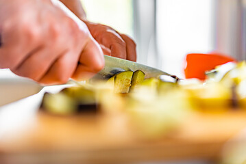 male hand cutting eggplant on cutting board at home kitchen