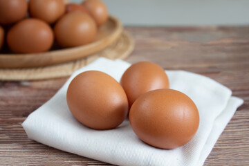 Chicken eggs three eggs on fabric are on table and in wooden plate