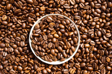 Java. Roasted coffee beans in a paper cup lid against the background of beans.
