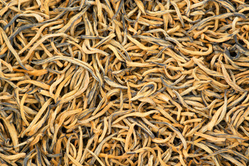 Jin Jun Mei Golden Eyebrows golden leaves hand-picked buds famous Chinese red tea. The famous Fujian variety of tea from the highlands of Wu Yi Shan. Closeup macro pattern background. Natural organic
