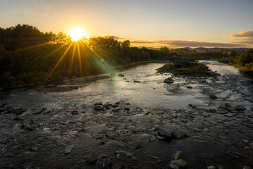 Sunset on the Poprad river.  Sun hides over trees. 