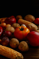 vegetables on a wooden table. dark. harvest. tomato, corn, apple, potato. Autumn Still Life