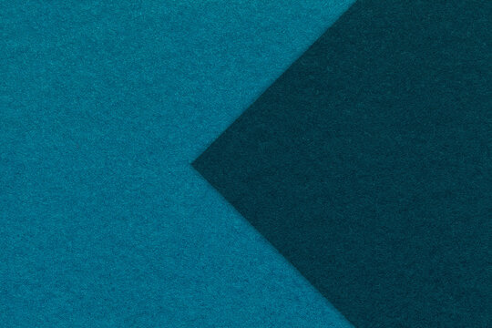 Texture of dark turquoise paper background, half two colors with navy blue arrow, macro. Craft cerulean cardboard.
