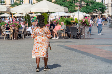 African American tourist on vacation abroad, people are relaxing in a summer restaurant in the background. Active lifestyle, travel, adventure and tourism concept.