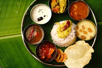 Kerala Ona sadya Onam feast - vegetarian thali served on a round plate with banana leaf