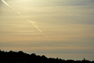Sunset sky with cloud lines and airplane contrail. Horizontal chill view.