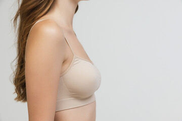 Cropped image of slender female body, breast and shoulders isolated over grey studio background....
