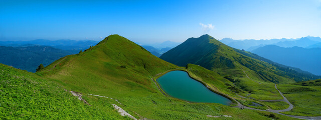 Panoramic view of Kanzelwand / Fellhorn in Kleinwalsertal in Austria, overlooking mountain lake and mountains with lush green meadow and blue sky - mountains landscape background banner panorama