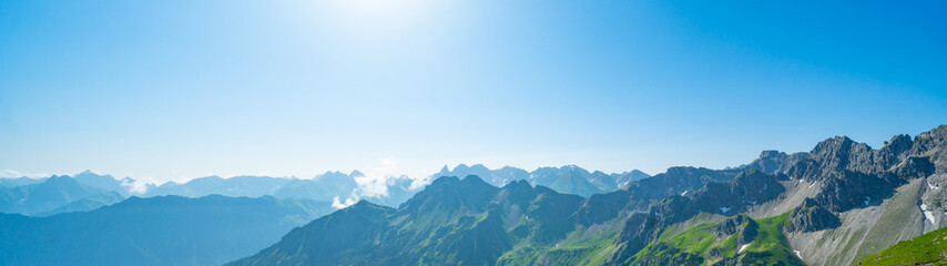 Panoramic view from Nebelhorn in Oberstdorf Allgäu Bavaria Germany - Beautiful Alps with lush green meadow and blue sky - Mountains landscape background banner panorama.