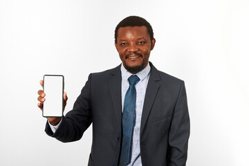 Smiling african american black man in business suit with smartphone blank mockup in hand, white wall background. Portrait of happy black businessman holding white phone mock up for advertising