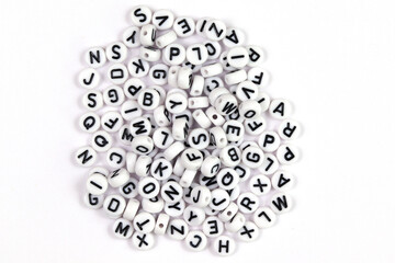 White beads with letters of the English alphabet on a white background. The concept of the development of thinking, grammar. View from above