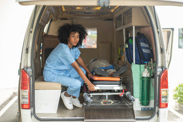African-American female nurse sits in an ambulance to pick up an elderly patient who has been in a hospital bed. Send to the hospital emergency room