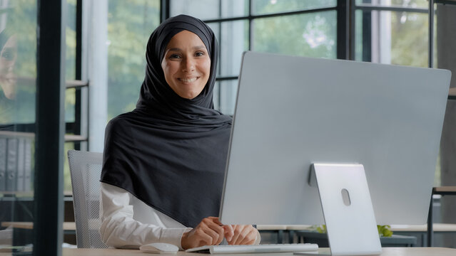 Confident successful elegant arab businesswoman typing on computer attractive muslim female in hijab professional worker experienced manager entrepreneur working in modern office posing in workplace