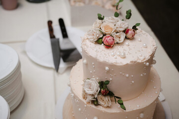 wedding white cake with tiers decorated with rose flowers on the table
