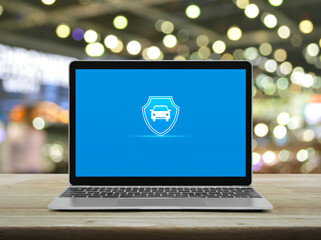 Car with shield flat icon on modern laptop computer monitor screen on wooden table over blur light and shadow of shopping mall, Business automobile insurance online concept