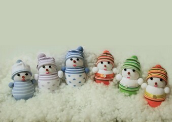Handmade snowmen in colorful clothes on a white background