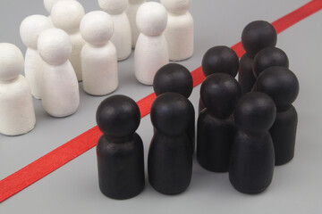 White and black wooden people figures separated by red line as border.