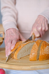 Age healthy woman cuts into pieces whole unleavened bread for breakfast or snack. View from above